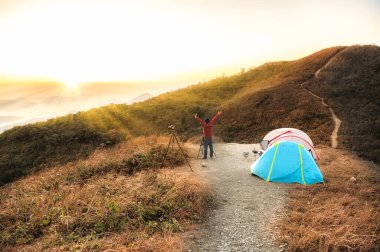 Kamp malzemelerinin yanındaki dağların tepesinde fotoğraf çeken gezgin, Kowloon Tepesi 'nde yürüyüş yapan (Fei Ngo Shan) Hong Kong' da sağlıklı, aktif yaşam tarzı olan insanlar. 