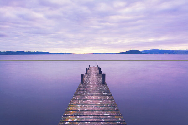 Romantic scene at a pier looking out upon Lake Rotorua at sunrise