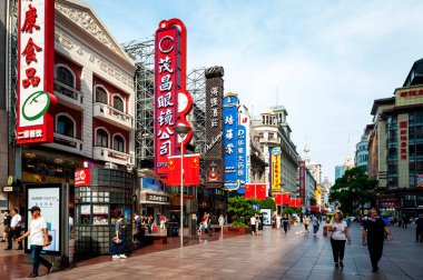 Şangay, Çin - Eylül 2019: Çin 'in Şangay şehrinin merkezindeki en işlek alışveriş caddesi olan Nanjing Yolu' nun doğu kesimindeki ticari binalarla yürüyen insanlar paralel düştü.