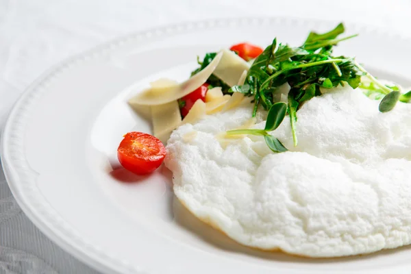 Rukola, peynir ve kiraz domates ile Kabarık Yumurta Beyaz Omlet. Beyaz tabak. Sarısı olmadan.