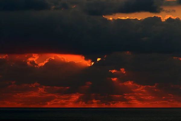 Star Sun against the background of thunderclouds and red sky at sunset