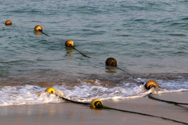 Akdeniz kıyısında kumlu bir sahilde yüzen şamandıralı bir ip. Güneşli bir günde deniz kıyısında. 