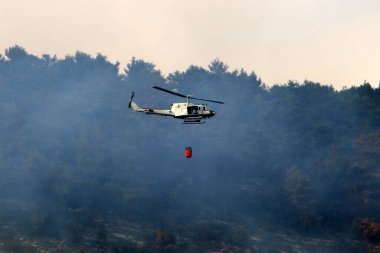 İsrail-Lübnan sınırındaki bir orman yangınını bir helikopter söndürdü. Ağaçlar ve çimenler yanıyor. 