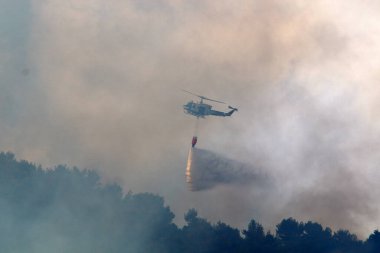 İsrail-Lübnan sınırındaki bir orman yangınını bir helikopter söndürdü. Ağaçlar ve çimenler yanıyor. 