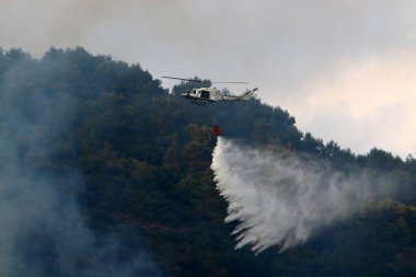 İsrail-Lübnan sınırındaki bir orman yangınını bir helikopter söndürdü. Ağaçlar ve çimenler yanıyor. 