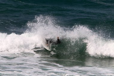 Kuzey İsrail 'deki Akdeniz' de yüksek dalgalarda sörf yapmak. Özel bir sörf tahtasında büyük bir deniz dalgasının tepesinde süzülüyordu.. 
