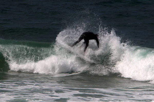 Surfing high waves in the Mediterranean Sea in northern Israel. Gliding along the crest of a large sea wave on a special board.