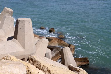 Akdeniz kıyılarındaki fırtına dalgalarından sahili korumak için dalgalı sulara devasa beton bloklar ve büyük taşlar konur. 