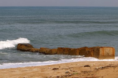 Akdeniz kıyılarındaki fırtına dalgalarından sahili korumak için dalgalı sulara devasa beton bloklar ve büyük taşlar konur. 