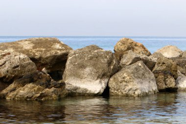 Akdeniz kıyılarındaki fırtına dalgalarından sahili korumak için dalgalı sulara devasa beton bloklar ve büyük taşlar konur. 