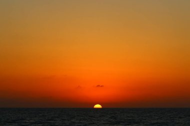 Güneş ufukta gökyüzünün alevli kırmızı ışığına karşı batar. 