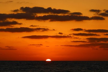 Güneş ufukta gökyüzünün alevli kırmızı ışığına karşı batar. 