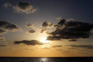 Güneş ufukta gökyüzünün alevli kırmızı ışığına karşı batar. 