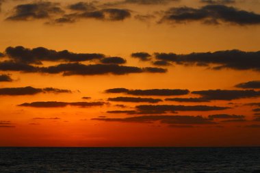 Güneş ufukta gökyüzünün alevli kırmızı ışığına karşı batar. 