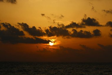Güneş ufukta gökyüzünün alevli kırmızı ışığına karşı batar. 