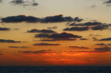 Güneş ufukta gökyüzünün alevli kırmızı ışığına karşı batar. 