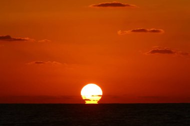 Güneş ufukta gökyüzünün alevli kırmızı ışığına karşı batar. 