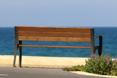 A bench for relaxation stands in a city park on the shores of the Mediterranean Sea on the Sesere of Israel 
