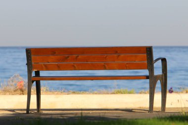 A bench for relaxation stands in a city park on the shores of the Mediterranean Sea on the Sesere of Israel 