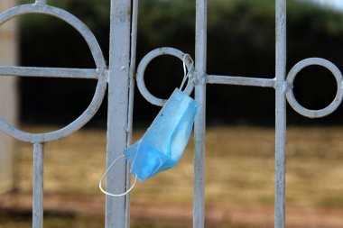 Corona virüsüne karşı korunmak için kullanılmış ve kirli bir tıbbi maske şehir parkında çöp gibi duruyor.. 