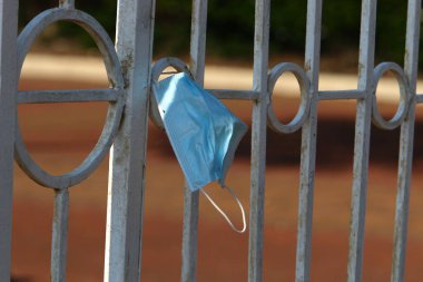 Corona virüsüne karşı korunmak için kullanılmış ve kirli bir tıbbi maske şehir parkında çöp gibi duruyor.. 