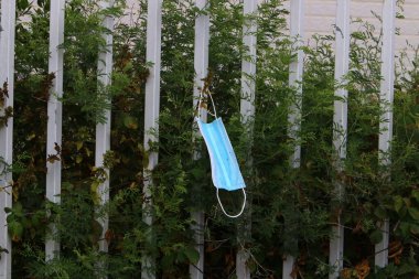 Corona virüsüne karşı korunmak için kullanılmış ve kirli bir tıbbi maske şehir parkında çöp gibi duruyor.. 