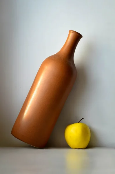 Керамическая бутылка и яблоко — стоковое фото