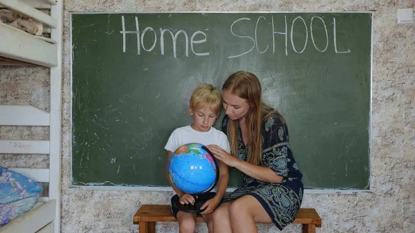 Home school concept. A mother gives her children a geography lesson with a globe in her hands.