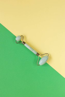 Yeşil Gua Sha yüz masajı aletleri. Sarı arka planda Yeşil Kuvars Yeşim Roller. Evde yaş, kaldırma ve tonlama karşıtı tedavi.