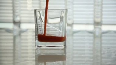 Domates suyu bir bardak dökülür. yakın çekim