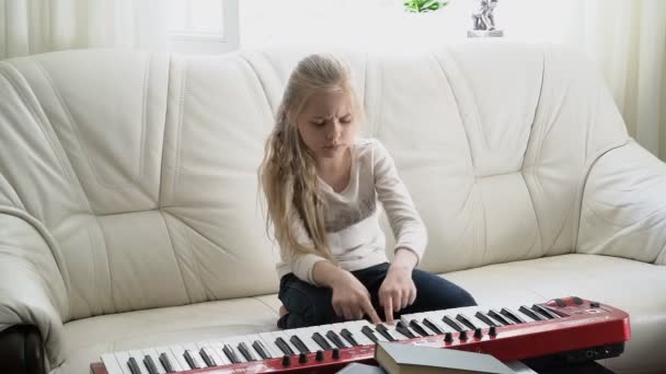 Красивая девушка, играющая на клавишах фортепиано MIDI — стоковое видео