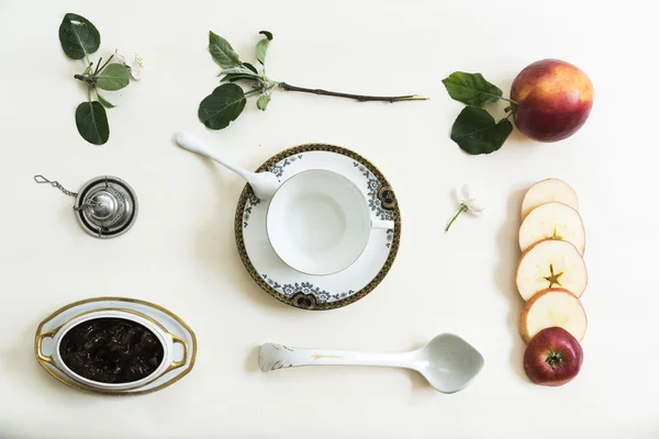 Κύπελλο, μαρμελάδα, μήλο και υποκατάστημα με λουλούδια σ ' ένα άσπρο τραπέζι. — Φωτογραφία Αρχείου