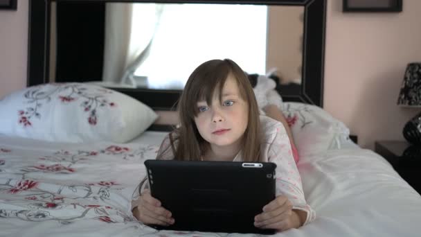 Meisje ligt op een bed en spelen van computerspel — Stockvideo