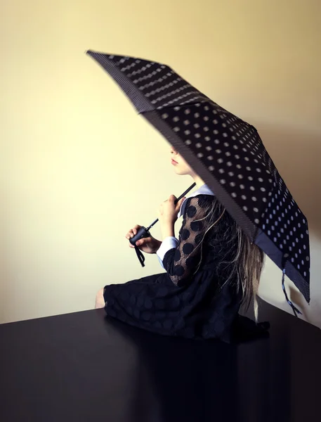 Beautiful blond girl with an umbrella on a background of bright walls — Stock Photo, Image