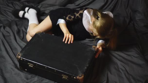 Mooi blond meisje kijkt in een oude koffer — Stockvideo
