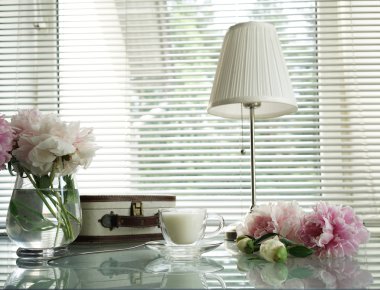 Yaz natürmort lambalar, el çantası, kupa ve peonies cam masa üzerinde okuma