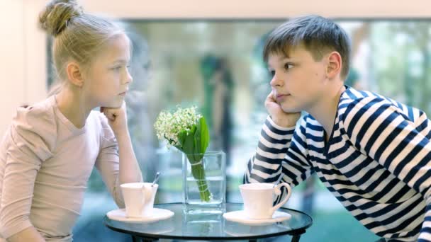 लड़की और लड़का गर्मियों की खिड़की की पृष्ठभूमि पर एक कैफे में चाय पी रहे हैं। एचडी सिनेमाग्राफ मोशन फोटो सीमलेस लूप — स्टॉक वीडियो
