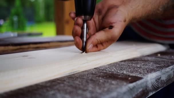 Carpenter borr att borra hål i styrelsen. händer närbild — Stockvideo