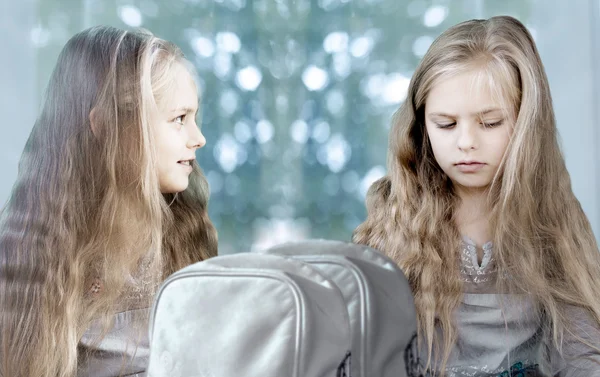 İkizler. Büyük pencere arka plan üzerinde okul sırt çantaları ile iki sevimli kız — Stok fotoğraf