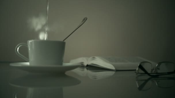 Vintage. una vieja película. taza sobre la mesa que se vierte agua hirviendo, libro y vasos en el fondo de la ventana. monocromo . — Vídeo de stock