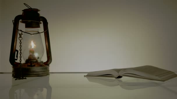 Vintage. una vieja película. mesa de cristal con libros y queroseno Lamrim. mano pone en gafas libro — Vídeos de Stock