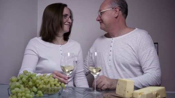 Jantar romântico. um homem e uma mulher de meia-idade com copos de vinho, uvas e queijo — Vídeo de Stock