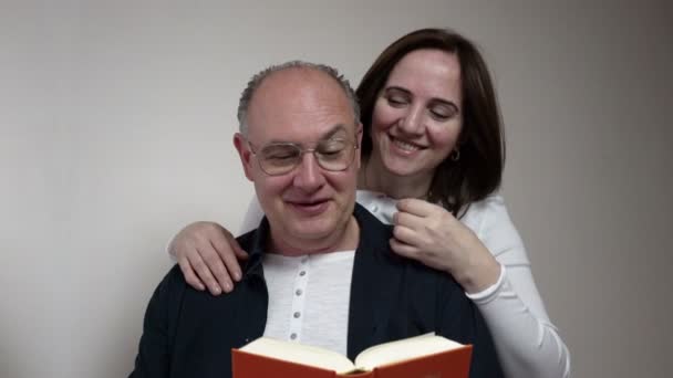 Romance. un hombre y una mujer de mediana edad leyendo un libro y riendo — Vídeos de Stock