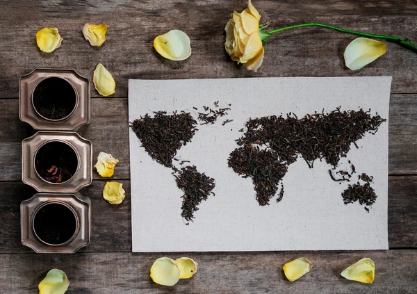 dünya haritası, eski kağıt üzerinde çay yaprakları ile kaplı. Avrasya, Amerika, Avustralya, Afrika. Vintage. çay, gül, limon, rustik ahşap masa üzerinde çay tins. üst görünüm. düz yatıyordu