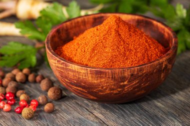 Güzel hazırlanmış ahşap bir kasede sanatsal yakın çekim, canlı kırmızı biber. Dokulu yüzey derinlik ve sıcaklık ekler, bu mutfak malzemesinin doğal güzelliğini arttırır..