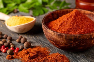 In this image, observe the striking detail of red ground pepper, displayed in a rustic wooden bowl. Ideal for use in food blogs, spice articles, and culinary stock photography.