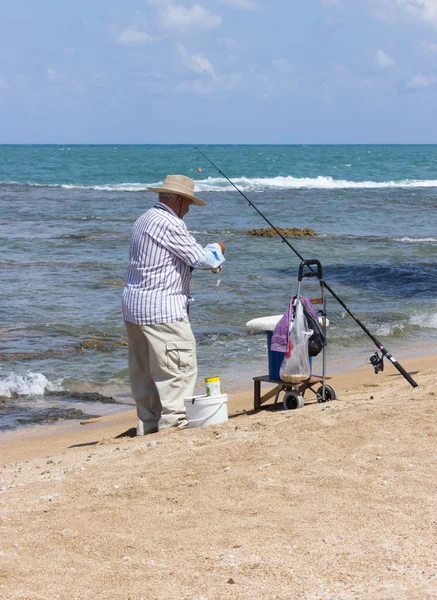 Elderly man fishing with a fishing rod — Stock Photo, Image