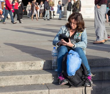 Woman sitting on the stairs reading a message on mobile phone clipart
