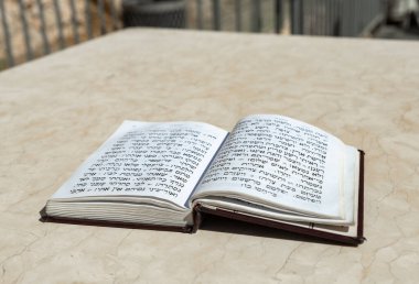 The open holy book of Jews with the text of prayers in Hebrew - Tehelim, lies on a table near the Western Wall in the old city. of Jerusalem in Israel clipart