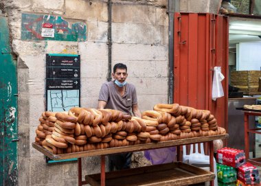 Kudüs, İsrail, 24 Ekim 2020: Eski Kudüs kentinin Müslüman kesimindeki Suq El Qatanin Caddesi 'nde çörekleriyle el arabasının yanında bir fırıncı duruyor.